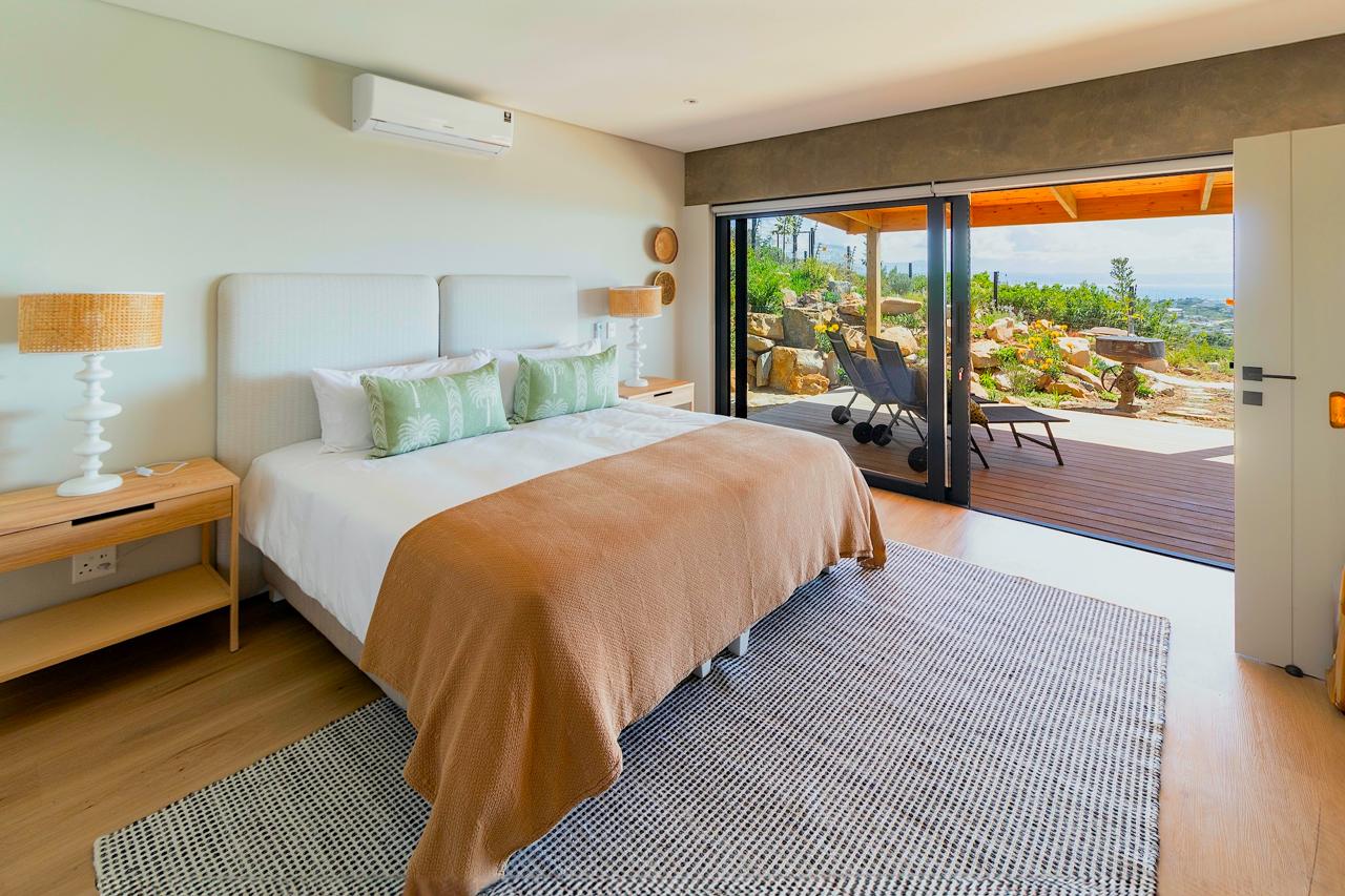 Serene bedroom with tan bedding, green pillows, and deck access