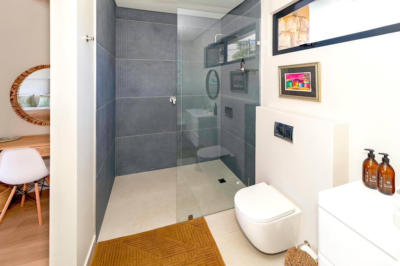 Modern bathroom with gray tiled shower and colorful artwork